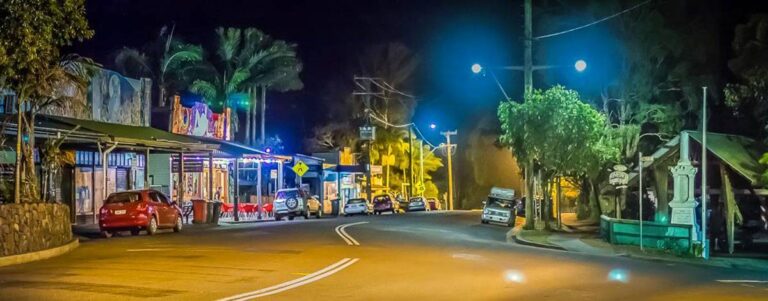 Colourful buildings and vibrant street art lighting up Nimbin town at night.