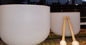 Close-up of quartz crystal singing bowls near a piano, resonating with harmonic vibrations.