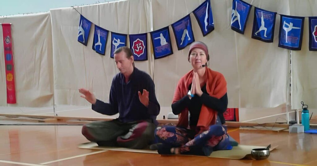 Penelope teaching yoga kriya while Trevor leads a group Reiki healing session.